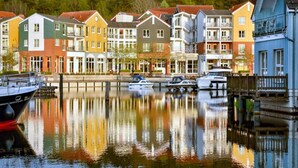 A row of colorful townhouses along a calm waterway with boats docked nearby. - 6 Person Holiday Park Home in Grosszerlang (Rheinsberg)
