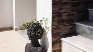 Una estatua de la cabeza de una mujer con una planta encima, ubicada en un pasillo con pared de piedra y un cartel que indica 'Piso 2'.