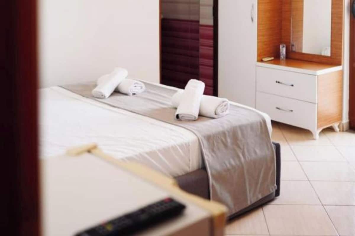 A hotel room with a bed, a wardrobe, a mirror, and an air conditioning unit.