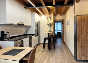 Een moderne keuken met een eethoek, houten balken in het plafond en uitzicht op de woonkamer.
