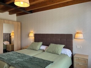 Ein Doppelbett mit zwei Kissen, ein Nachttisch, ein Spiegel und zwei Wandlampen.