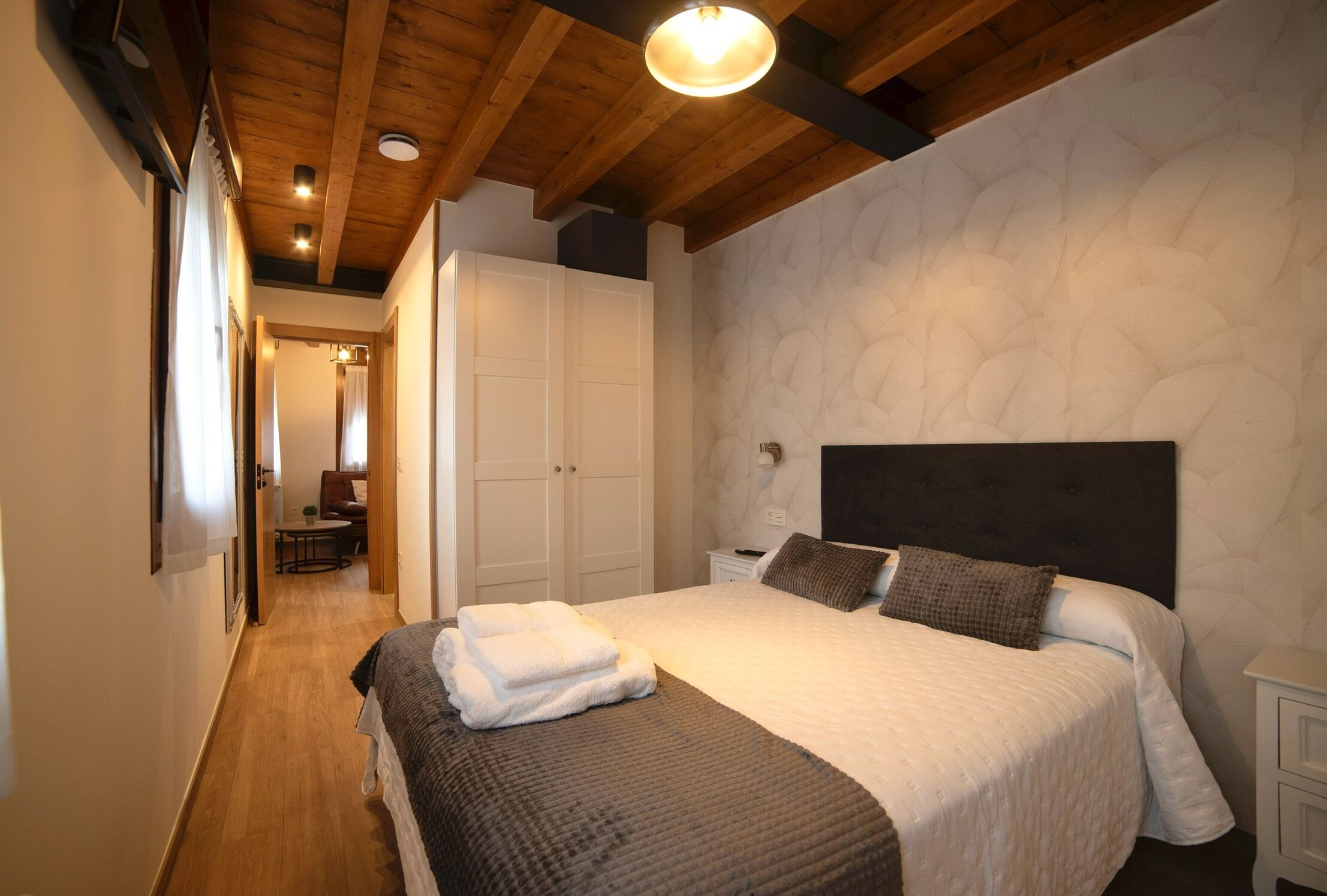 A bedroom with a large bed, a wardrobe, and a bedside table.