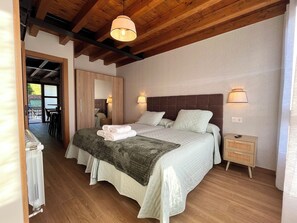 A bedroom with a bed, bedside lamps, a nightstand, and a view of the outside. - Apartment in the Picos de Europa, Asturias. Natural Paradise. (Onis)