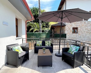 An outdoor patio area with wicker furniture, a table, and an umbrella. - Apartment in the Picos de Europa, Asturias. Natural Paradise. (Onis)