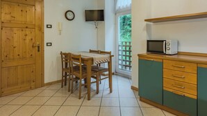 A kitchen with a dining table, chairs, a microwave, cabinets, a clock, and a window with a view of greenery. - Beautiful apartment for 4 people with WIFI and TV (San Bernardo)
