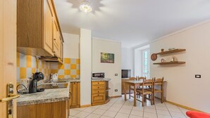 A compact kitchen with wooden cabinets, a microwave, and a dining area with a table and chairs. - Beautiful apartment for 4 people with WIFI and TV (San Bernardo)