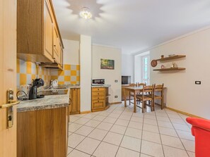 Eine kleine Küche mit Holzausstattung, einer Mikrowelle und einem Essbereich mit Tisch und Stühlen.