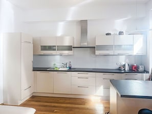 Une cuisine moderne avec des meubles blancs, un plan de travail noir et un revêtement de sol en bois.
