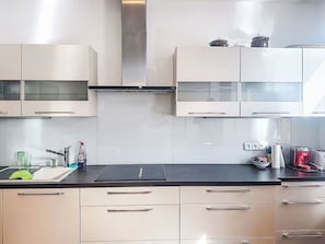 A modern kitchen with white cabinets, a black countertop, and stainless steel appliances.
