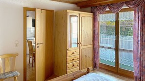 A room with a bed, wooden wardrobe, and a chair.