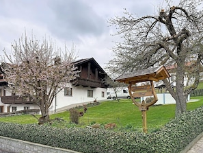 Ein traditionelles Chalet mit Holzdach, einem Schild mit Wolfsdarstellung und einem gepflegten Garten.