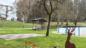 Un parc agrémenté d’une sculpture de cerf, d’un espace de repos abrité et d’une aire de jeux pour enfants.