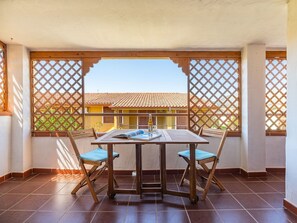 Ein Balkon mit Tisch, Stühlen, einer Flasche und einer Zeitschrift.