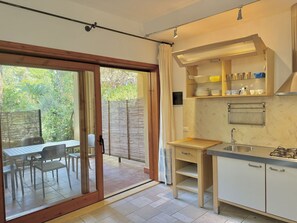 Une cuisine avec une porte-fenêtre coulissante donnant sur un espace extérieur aménagé pour se détendre.