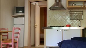 Una cucina compatta con fornello, lavello e zona pranzo con una sedia.