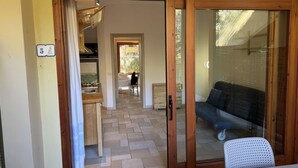 Una stanza con una porta scorrevole in vetro che dà su un balcone, angolo cottura e un letto con testiera scura.