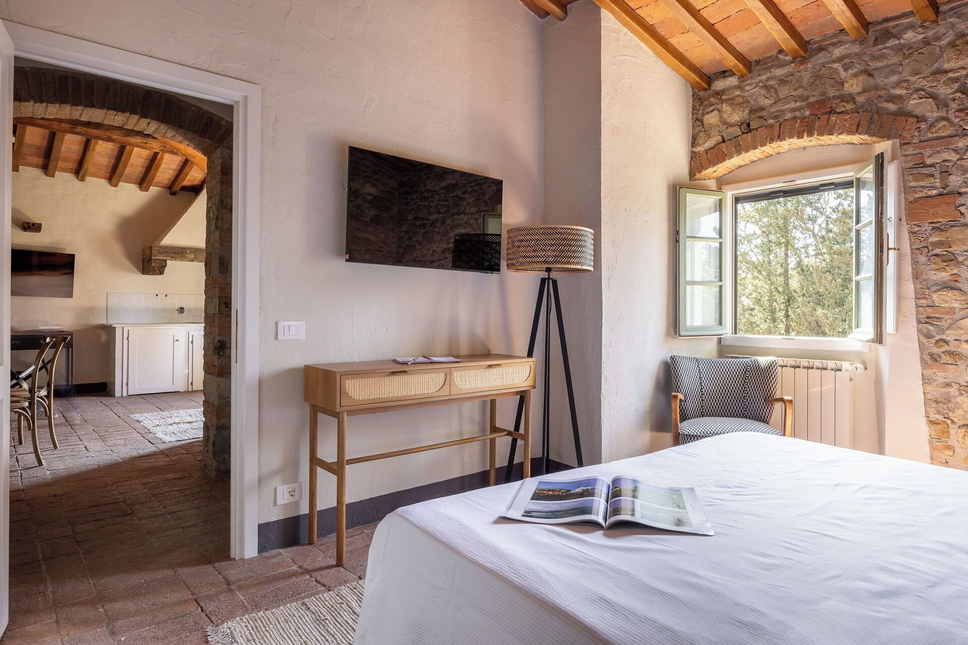 A bedroom with a bed, a desk, a chair, a lamp, and a window.