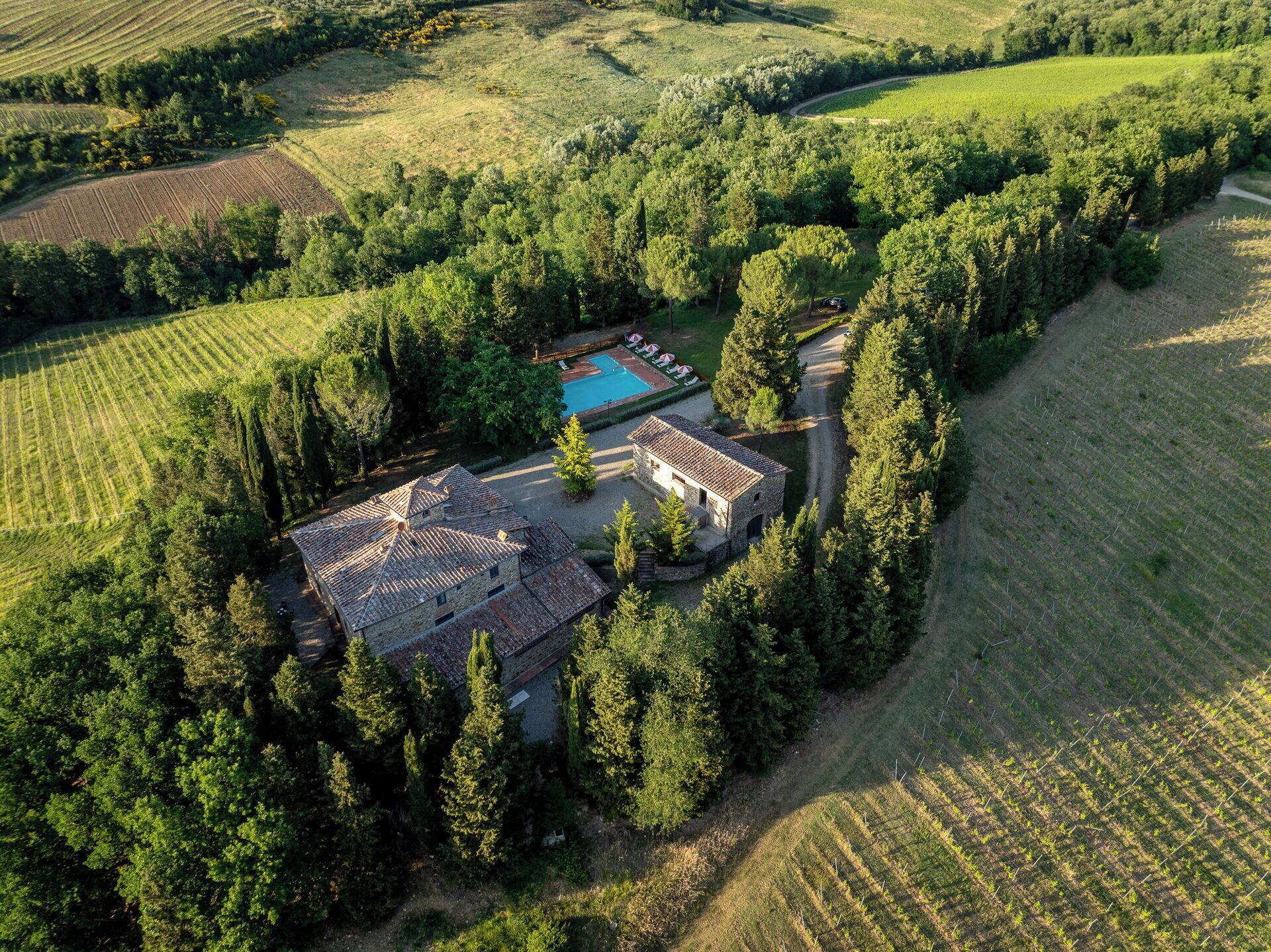 Vista aérea de una propiedad con un edificio de piedra, piscina y campos circundantes.