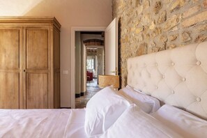 Ein Schlafzimmer mit einer Steinwand, einem Holzschrank und einem gepolsterten Kopfteil.
