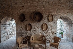 Ein rustikales Interieur mit Steinwänden, Korbmöbeln und Steinböden.