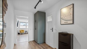 Ein Flur mit Holzboden, einem grauen Schrank, einem schwarzen Kühlschrank und einer Karte von Bremen an der Wand.