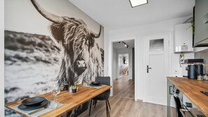 Eine moderne Küche mit einer großen Wandmalerei eines Stiers, Holzboden und einem Essbereich mit Tisch für zwei Personen.