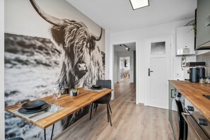 Eine moderne Küche mit einer großen Wandmalerei eines Stiers, Holzboden und einem Essbereich mit Tisch für zwei Personen.