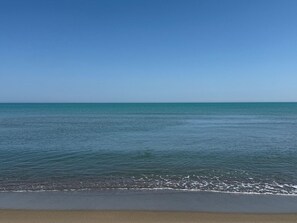 Ein Strand mit ruhigem Wasser und blauem Himmel.