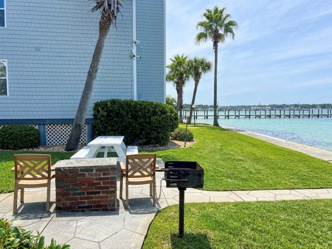 Eine Terrasse mit Tisch und Stühlen, einem Briefkasten und Blick auf das Wasser mit einem Steg im Hintergrund.
