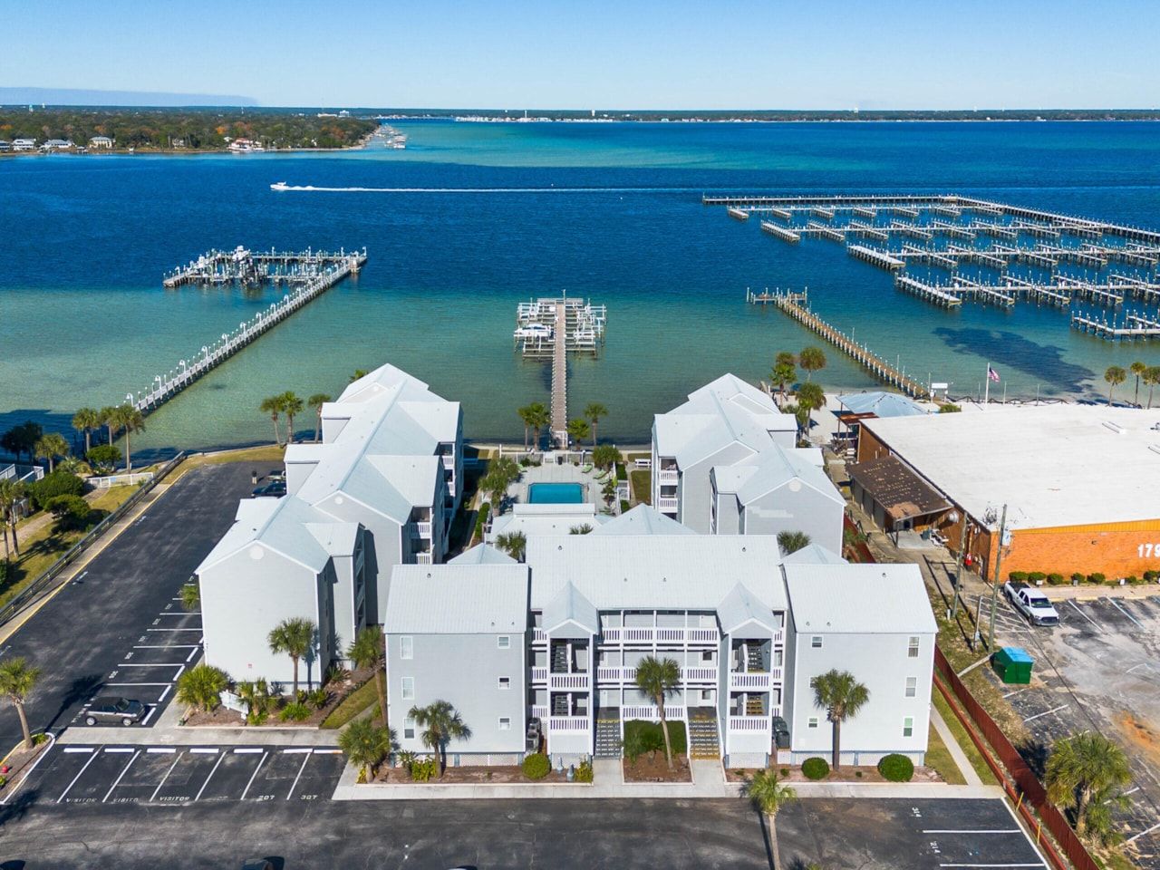 A coastal hotel with multiple buildings, a marina, and a clear view of the ocean.