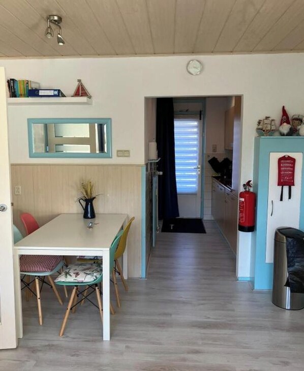 A compact kitchen with a dining area, a visible fire extinguisher, and a clock on the wall.