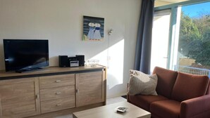 Una sala de estar con televisor, mueble de madera, sofá y una mesa.