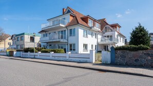 Kerrostalo, jossa on useita kerroksia, parvekkeita, kiviseinä ja portilla varustettu sisäänkäynti.
