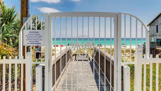Ein verschlossenes Tor zu einem Strandbereich, mit einem Schild, das anzeigt, dass es sich um privates Eigentum handelt und der Zutritt nur Eigentümern und Gästen vorbehalten ist.