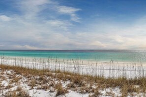 En strand med kristallklart turkost vatten, vit sand och gles vegetation.
