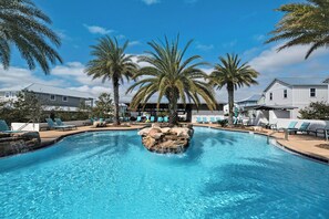 Una piscina con sillas de descanso, palmeras y un edificio al fondo.