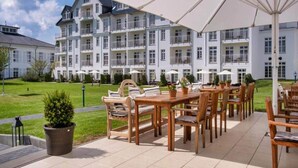 Ein Hotel mit Außenbereich, einem großen Sonnenschirm und einem gepflegten Rasen.