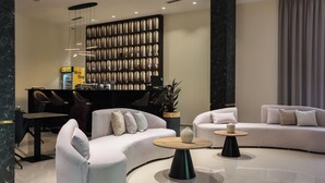 Eine moderne Lobby mit einer gebogenen Couch, einem runden Couchtisch und einem Empfangsbereich mit Vitrine.