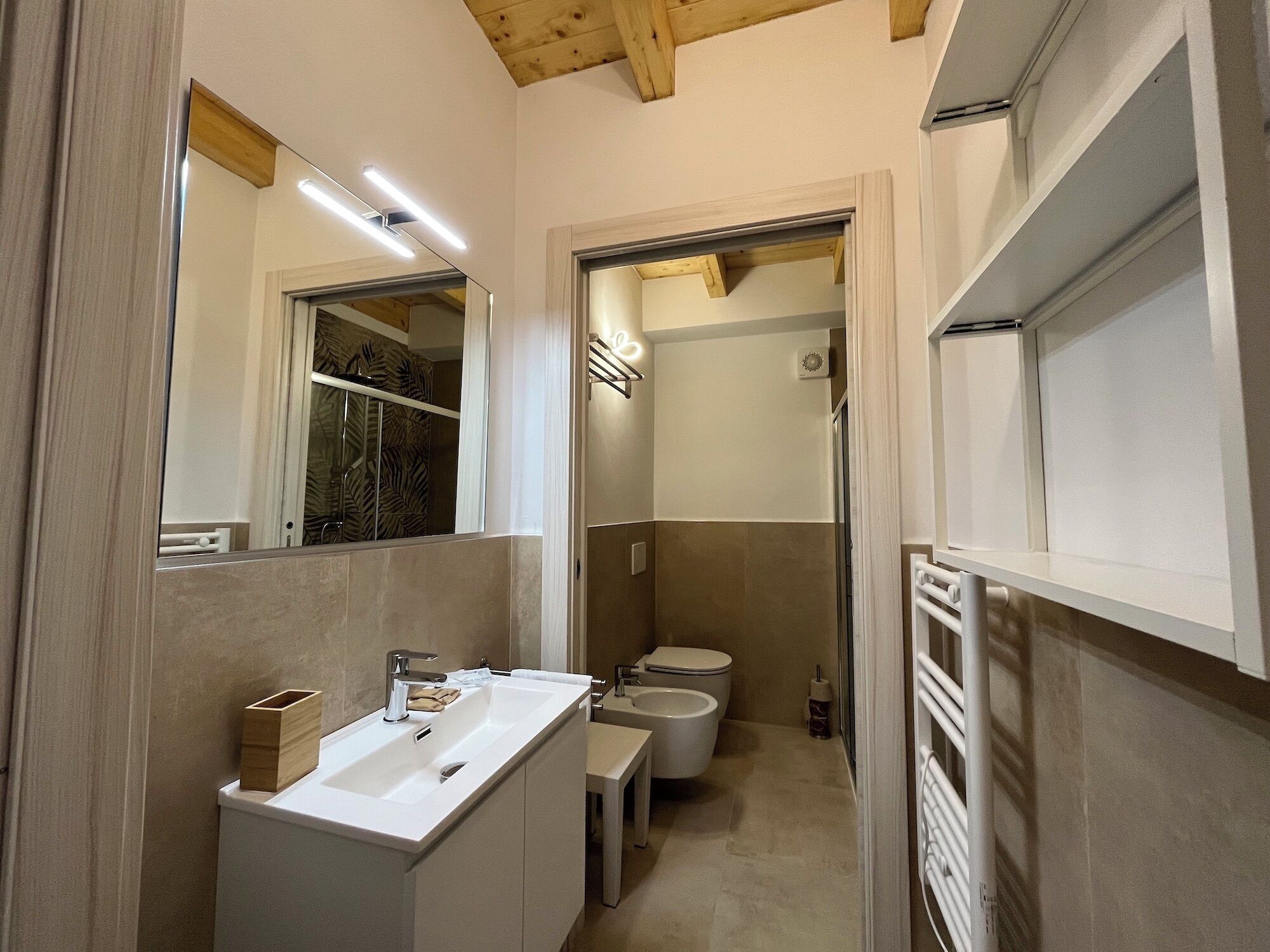 Une salle de bain moderne avec un lavabo blanc, un miroir et un espace douche.