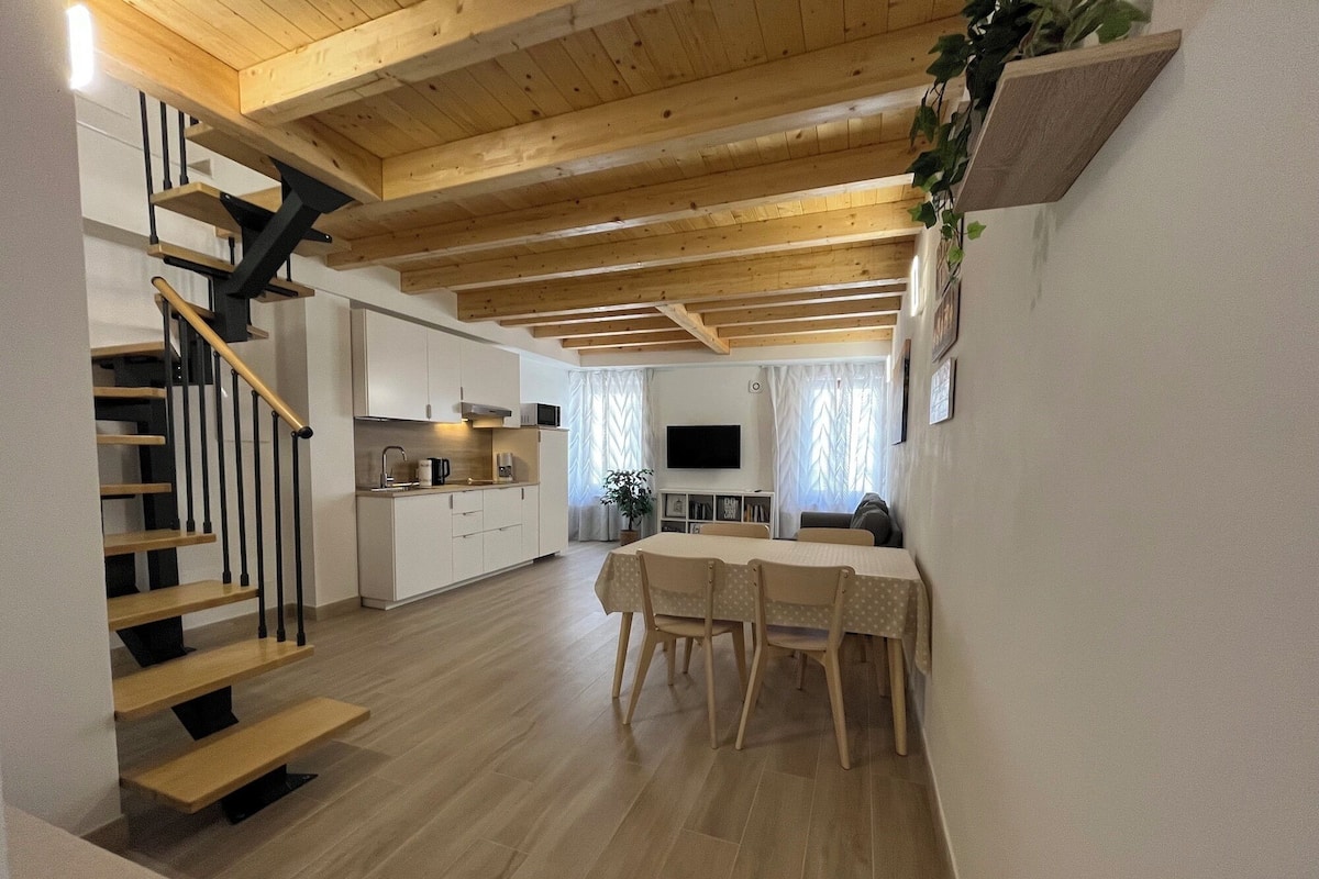 Eine moderne Küche mit weißen Schränken, ein Essbereich mit Tisch und Stühlen sowie eine Treppe mit Holzboden.