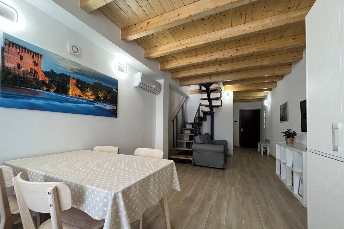 Ein Essbereich mit Tisch und Stühlen, eine Treppe und eine Küchenzeile.