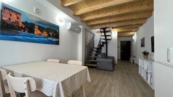 Un espace repas comprenant une table et des chaises, un escalier et un coin cuisine.