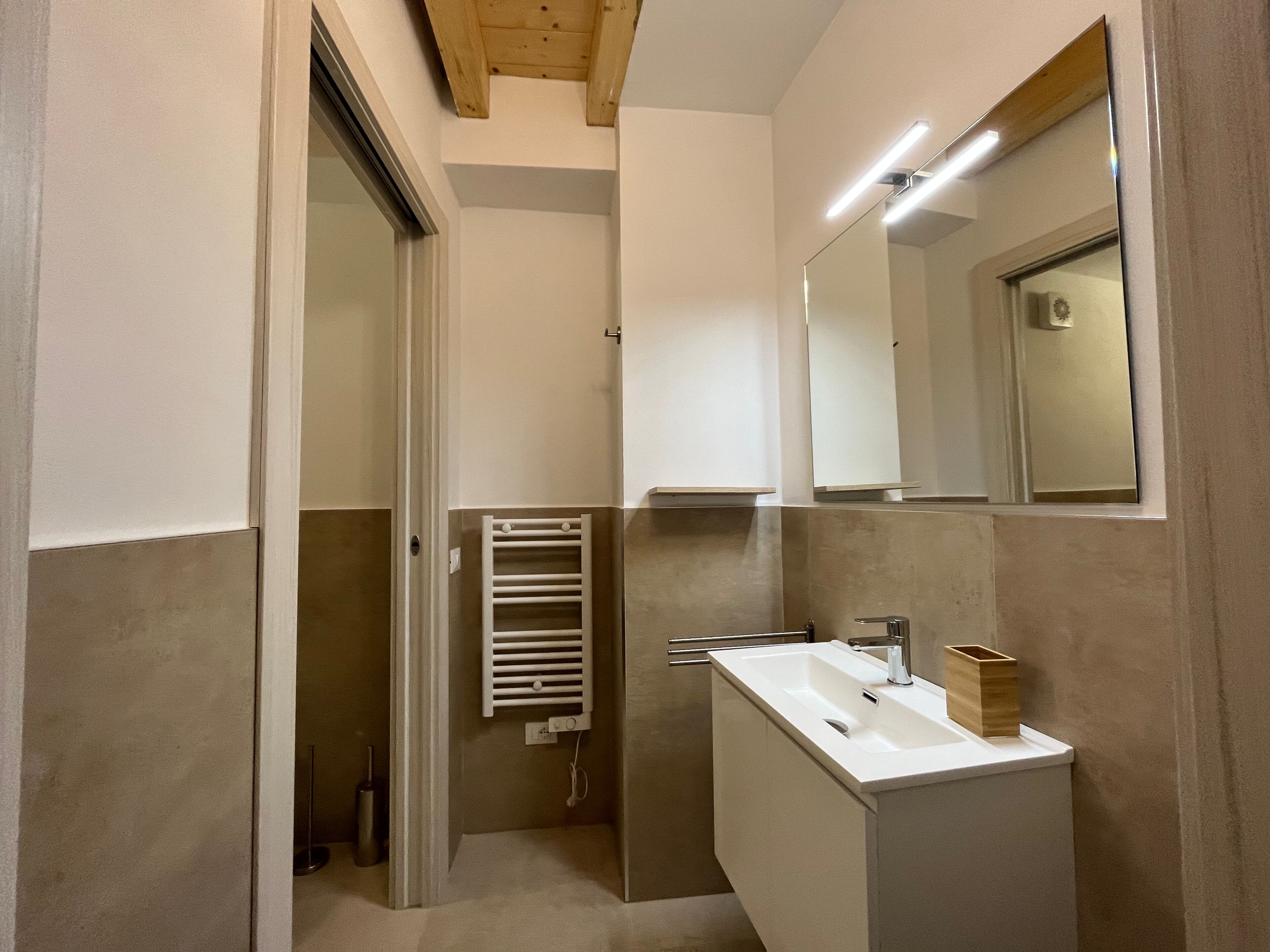 Ein modernes Badezimmer mit begehbarer Dusche, einem integriertem Waschbecken und einem Spiegel.