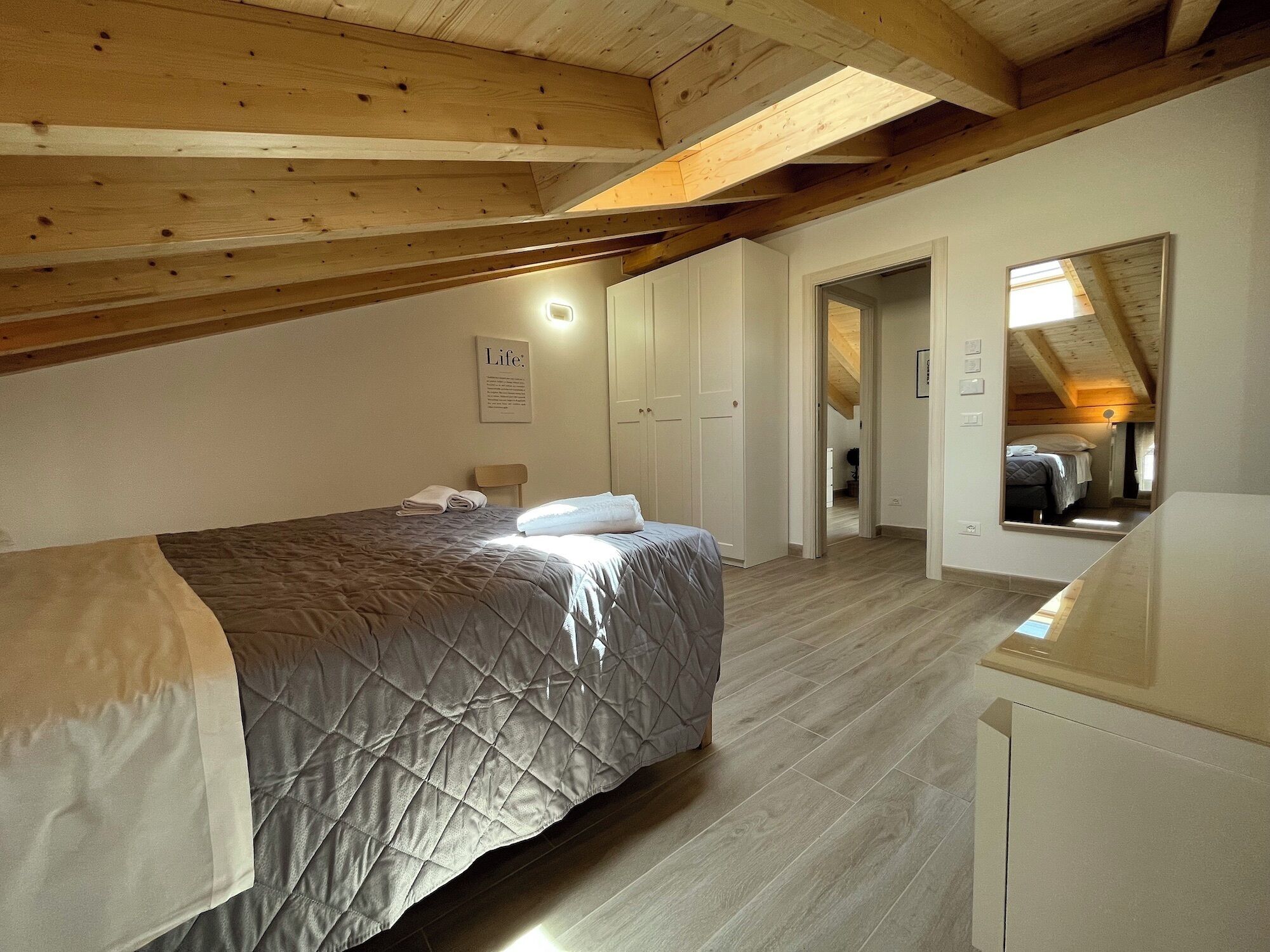 Una camera da letto con un letto, una sedia, una scrivania e uno specchio.