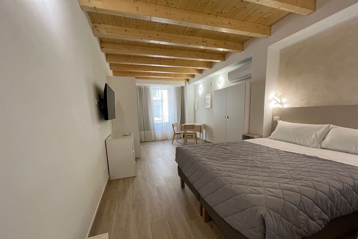 Ein Schlafzimmer mit Bett, Schreibtisch, Stuhl, Fernseher und Kleiderschrank.