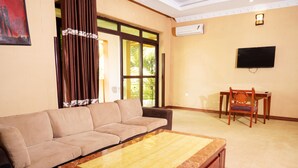 Una sala de estar con sofá, mesa de centro, televisor y comedor con una silla y mesa.