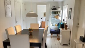 A dining area with a table, chairs, a hanging light fixture, a cabinet with glassware, and a door leading to another room. - 6 Person Holiday Home in Mellbystrand (Mellbystrand)