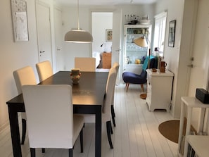 A dining area with a table, chairs, a hanging light fixture, a cabinet with glassware, and a door leading to another room. - 6 Person Holiday Home in Mellbystrand (Mellbystrand)