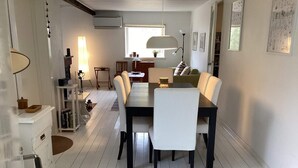 A dining area with a long table, white chairs, a lamp, and a bookshelf. - 6 Person Holiday Home in Mellbystrand (Mellbystrand)