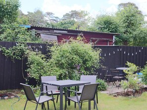 An outdoor patio with a table and chairs, surrounded by a wooden fence and greenery. - 6 Person Holiday Home in Mellbystrand (Mellbystrand)